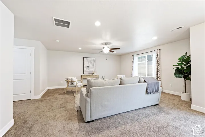 Spacious room featuring neutral carpeting, recessed lighting, a ceiling fan, and white baseboards