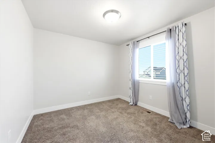 Office or bedroom. Carpeted room featuring a white-framed window with blinds, light gray walls, and a flush-mount ceiling light fixture