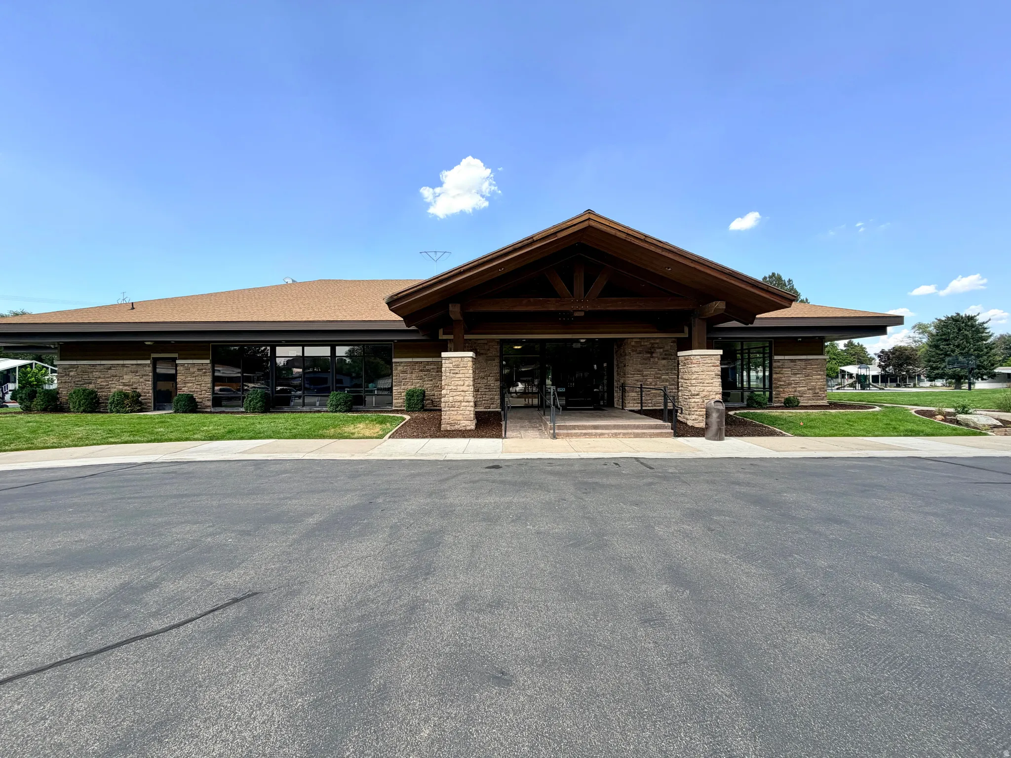 Contemporary building featuring a prominent stone facade, expansive glass windows, a deep overhang entryway, and a gabled roofline