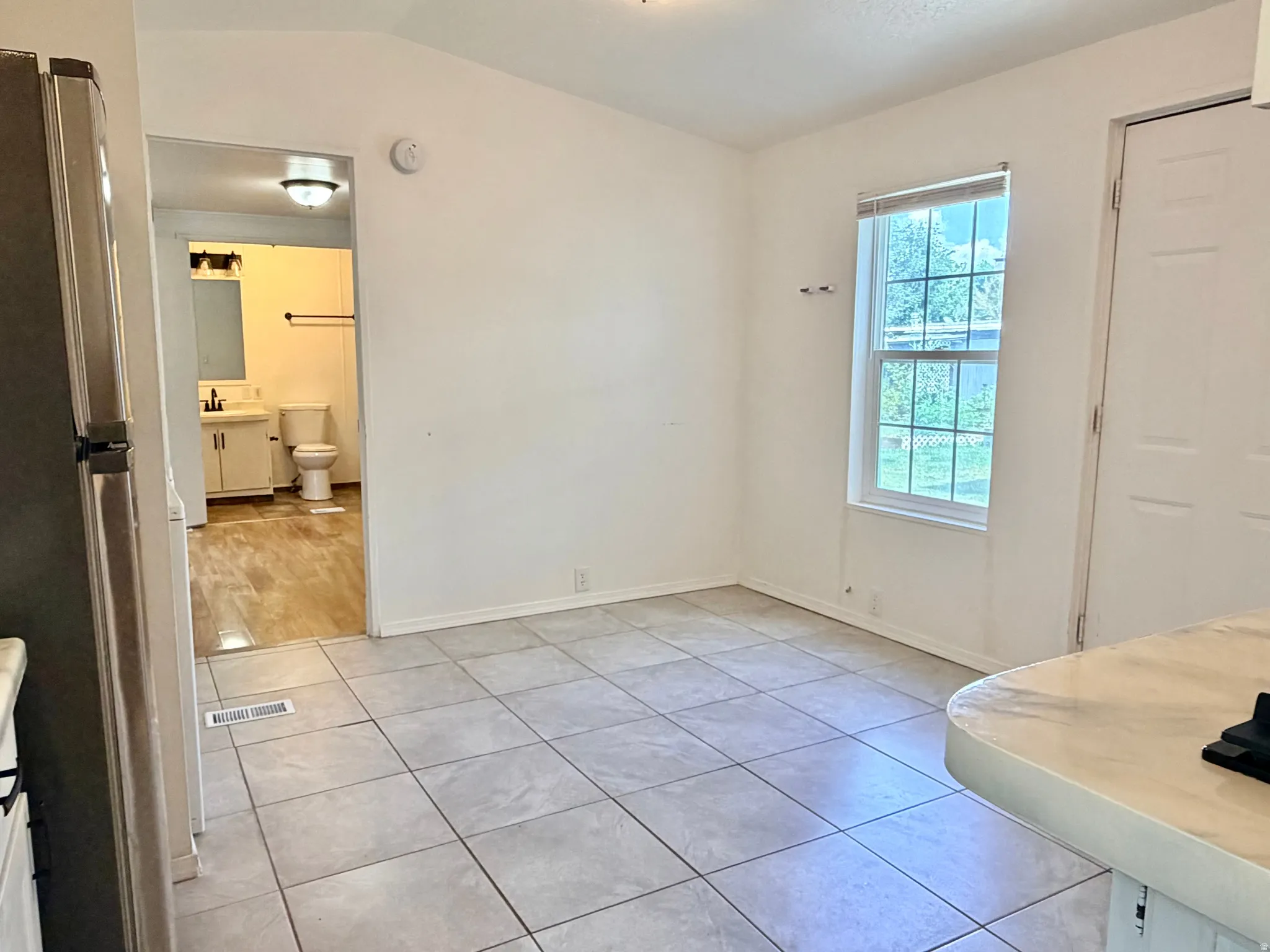 Open concept living space featuring neutral tile flooring, a window providing natural light, and a white paneled door