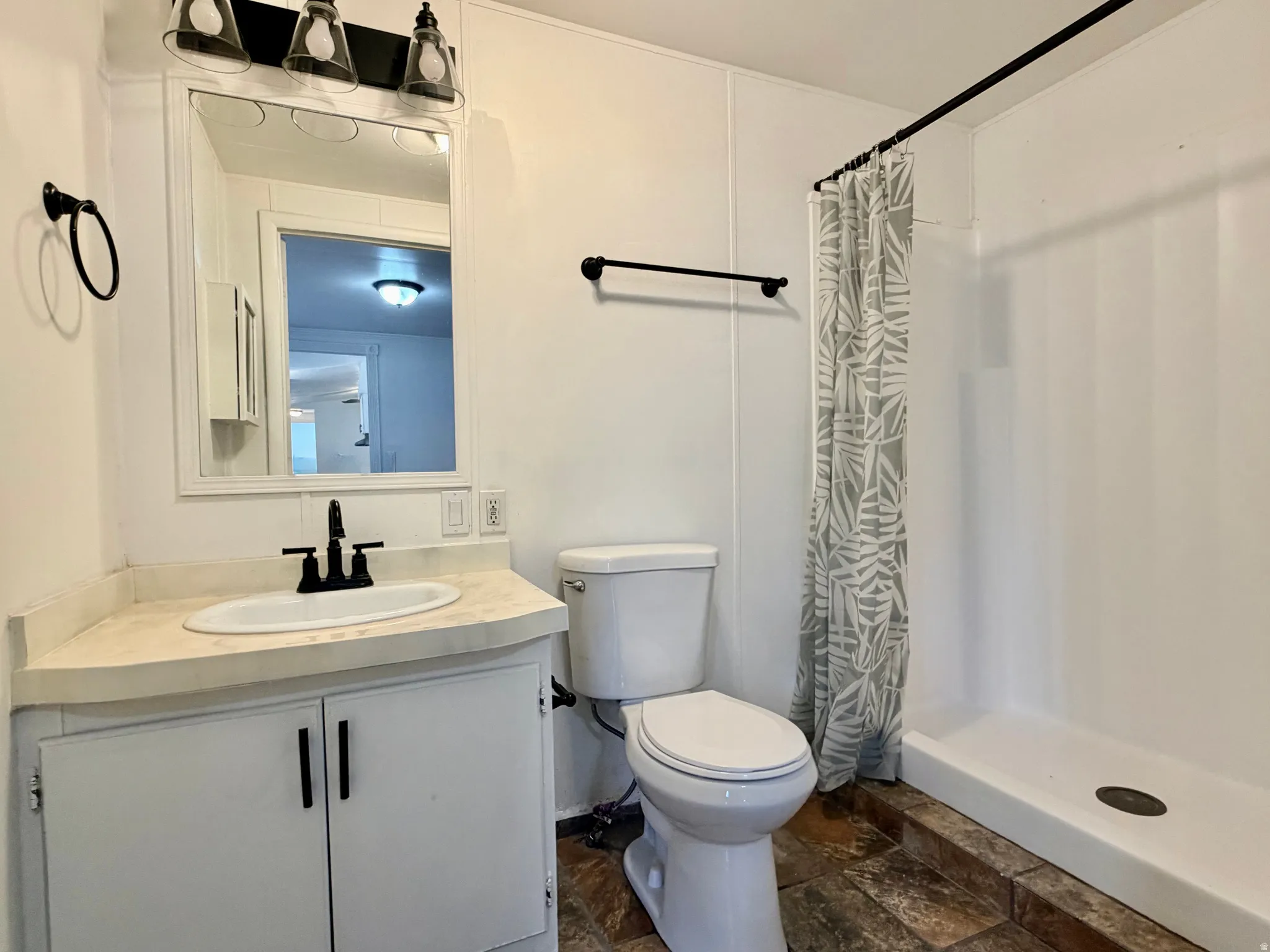 Bathroom featuring a white vanity with a corner-set countertop, under-mount sink, and matte black faucet