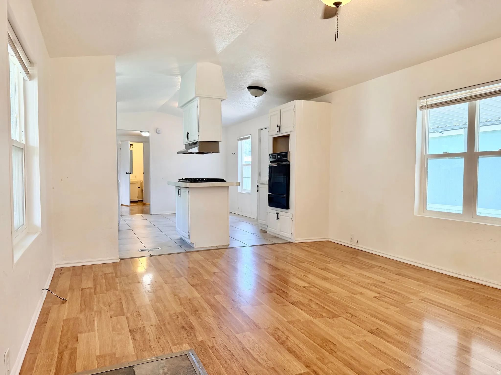 Expansive open-concept living area featuring wood-finish flooring, white walls, and a recessed ceiling light