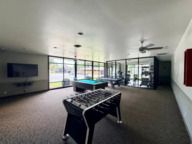 Recreational space featuring carpeted flooring, full-height window walls, a billiards table, and a foosball table