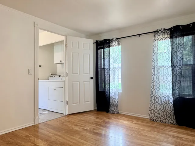 Wood-finish flooring throughout, bright white walls, and crown molding detail
