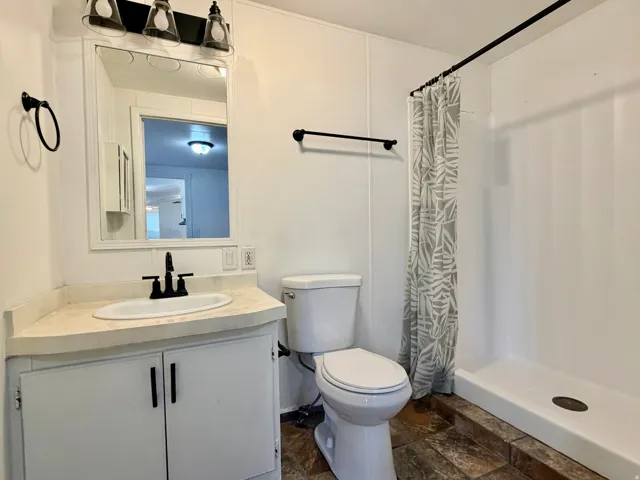 Bathroom featuring a white vanity with a corner-set countertop, under-mount sink, and matte black faucet