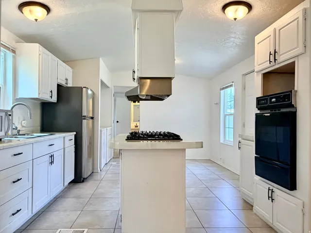 Kitchen featuring white cabinetry, light-toned countertops, tile flooring, and stainless-steel appliances