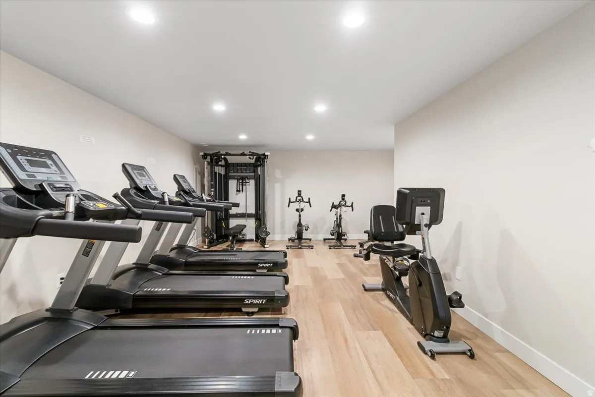 Dedicated fitness area featuring light wood-finish flooring, recessed lighting, and pale neutral walls