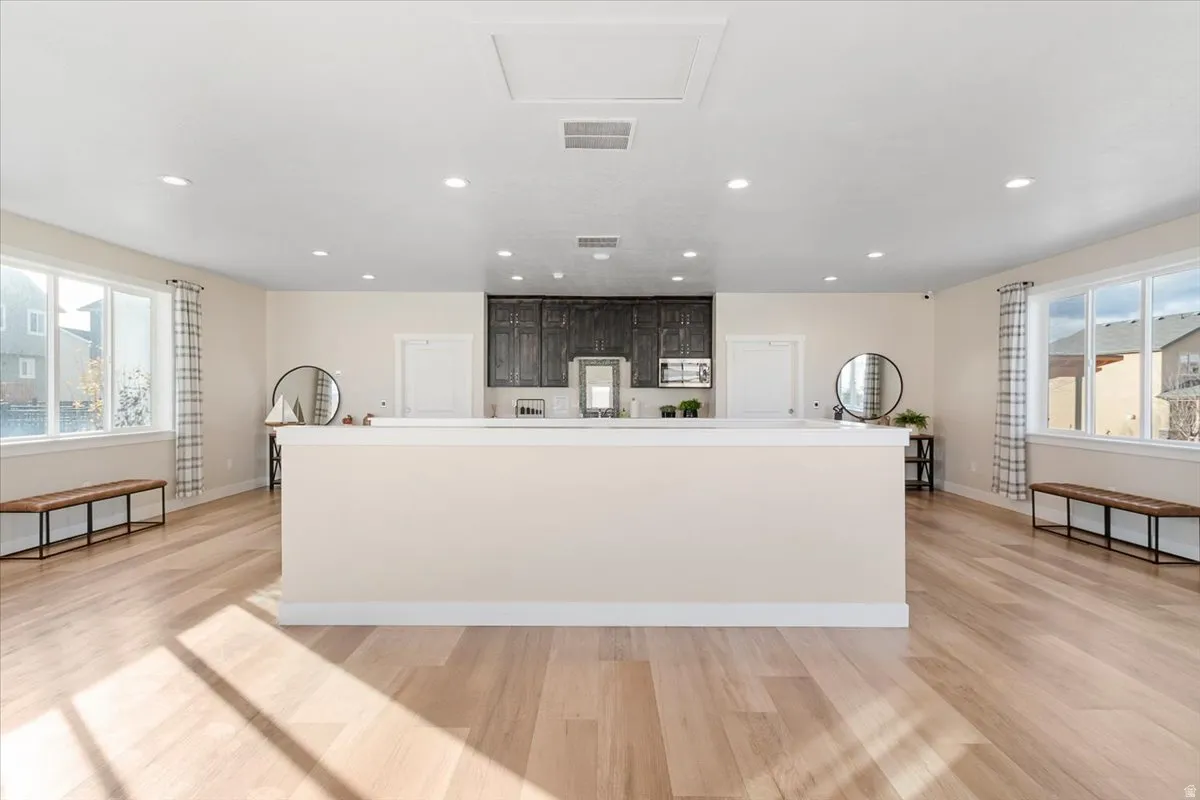 Expansive open-concept living area featuring light wood-finish flooring, recessed lighting, and large windows