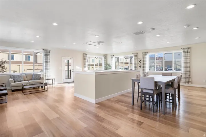 Spacious common area featuring wood-finish flooring, recessed lighting, expansive windows, and a dedicated dining zone