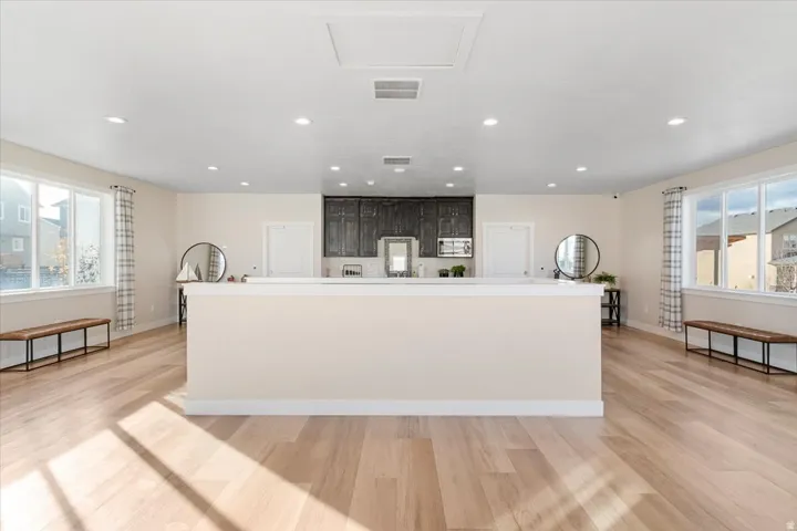 Expansive open-concept living area featuring light wood-finish flooring, recessed lighting, and large windows