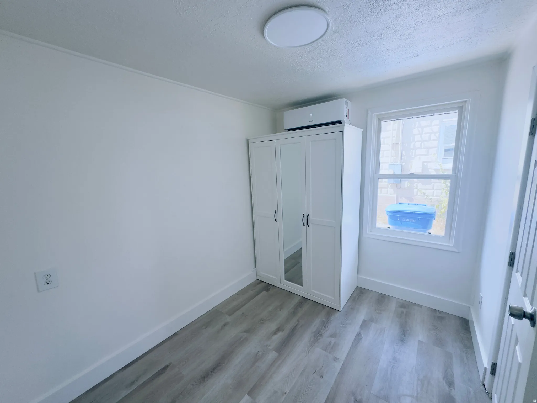 Interior room featuring wood-finish flooring, white baseboards, and white walls