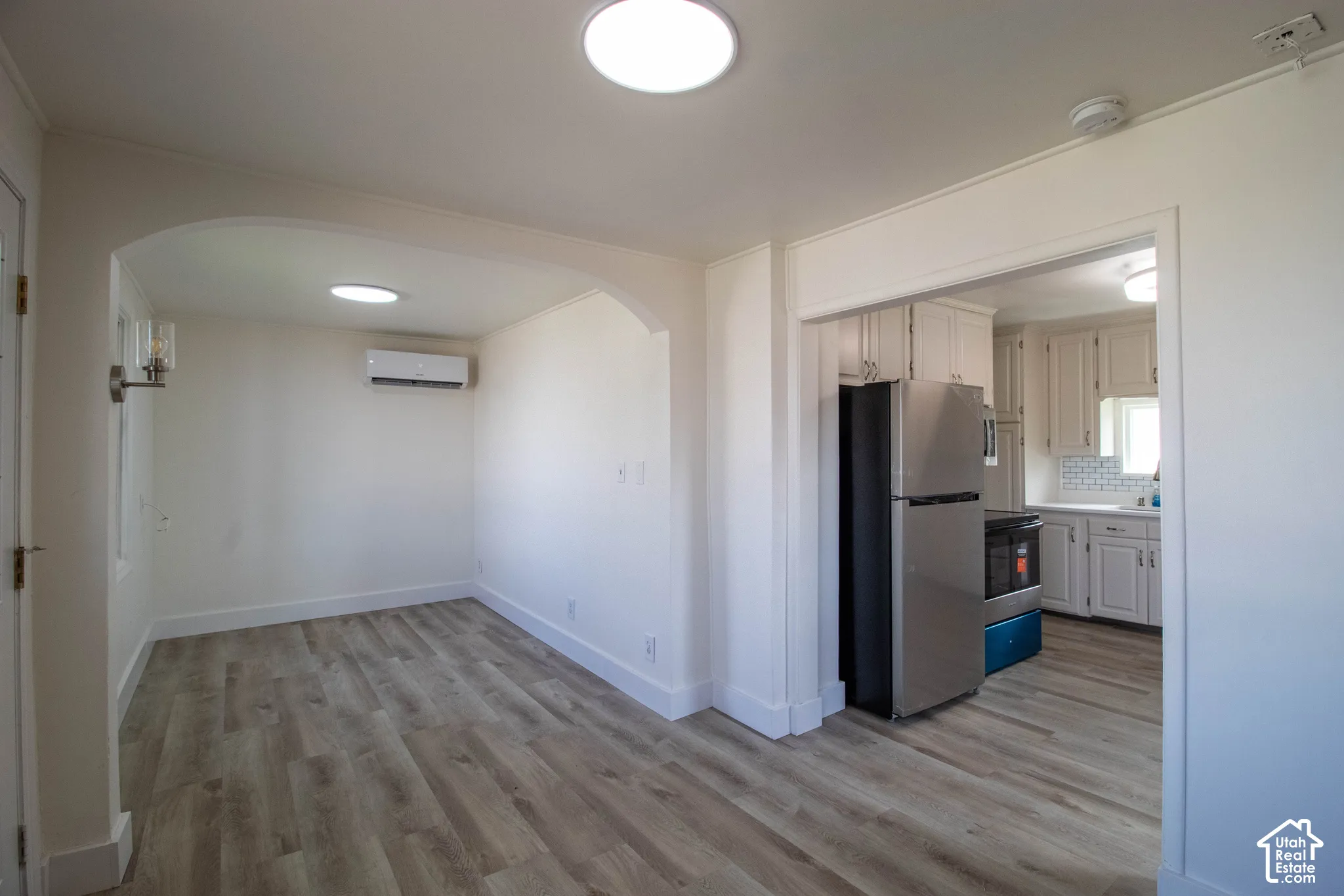 Spacious interior with wood-finish flooring, recessed ceiling lights, and an arched doorway