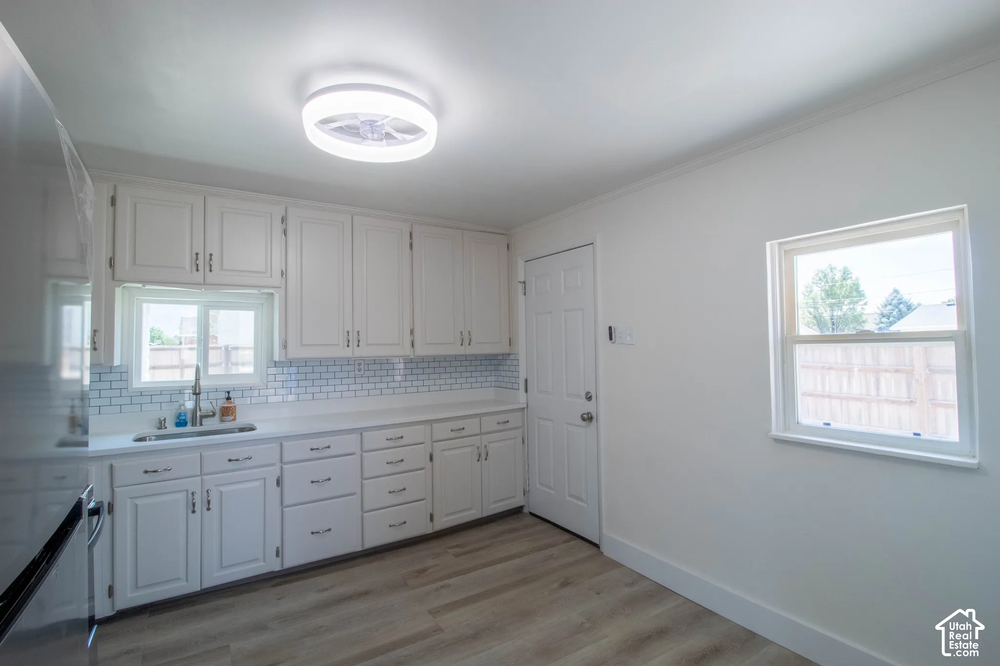 Kitchen featuring extensive white cabinetry, light-toned countertops, and a subway tile backsplash