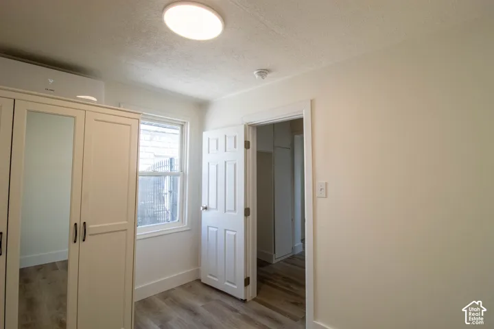 Bright room featuring wood-finish flooring, a double-hung window, and a built-in wardrobe with mirrored doors
