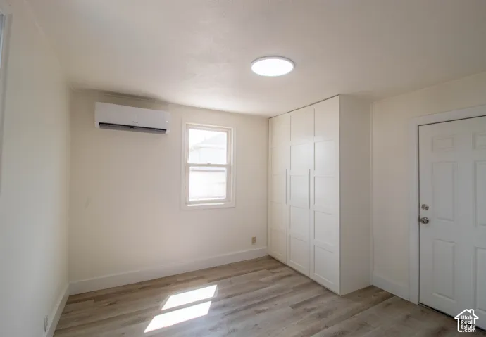 Bright room with wood-finish flooring, a contemporary ceiling light fixture, and a built-in white wardrobe system