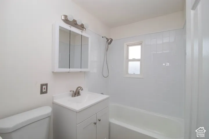 Bathroom featuring a white vanity with a single basin sink, brushed nickel faucet, and coordinating light fixture