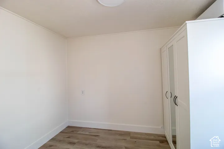 Compact room featuring wood-finish flooring and white baseboards