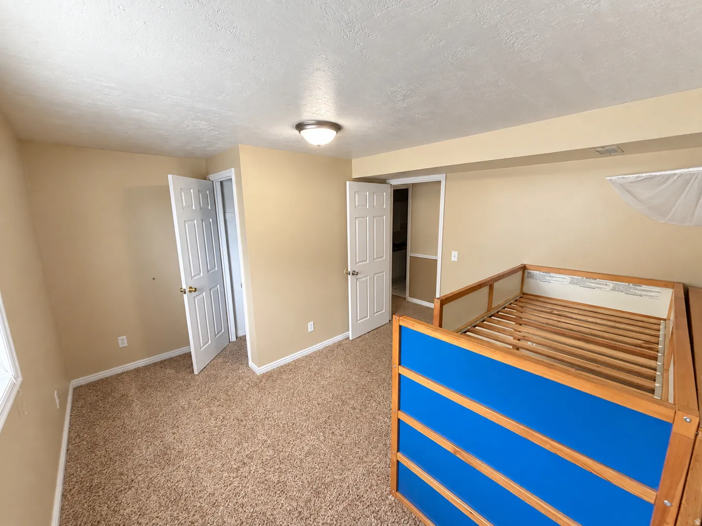 Neutral tone wall paint, textured ceiling, flush mount ceiling light fixture, carpet flooring, and white trim