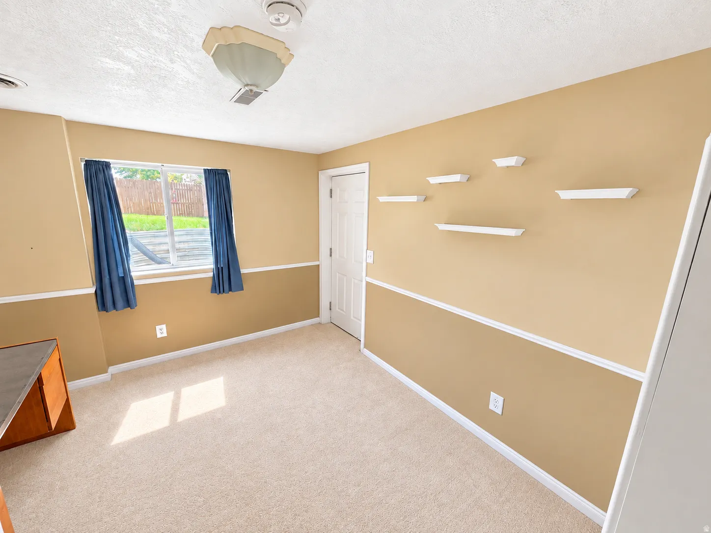 Neutral carpet flooring, two-tone painted walls with chair rail molding, and a window with exterior visibility