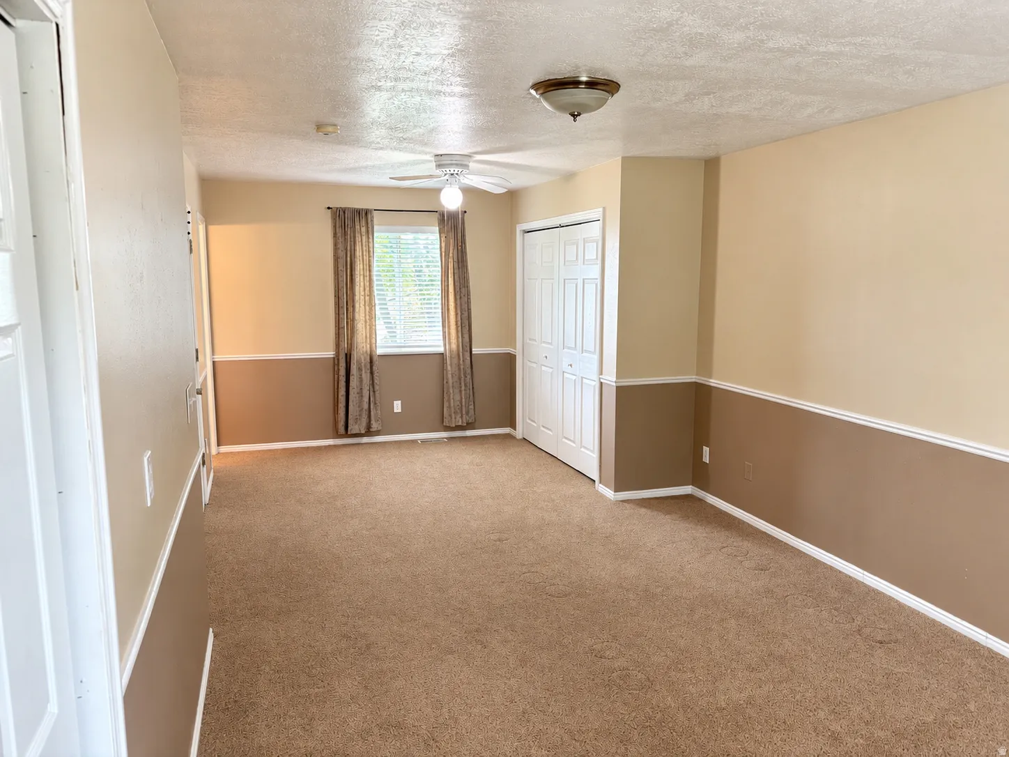Carpeted flooring, built-in bi-fold closet doors, ceiling fan, flush mount lighting, and window with blinds