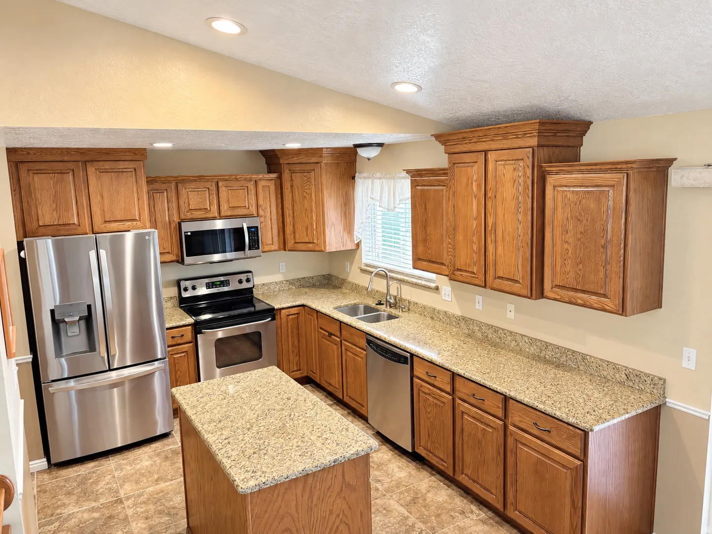 Kitchen featuring wood cabinetry, granite-finish countertops, stainless steel appliances, and recessed lighting