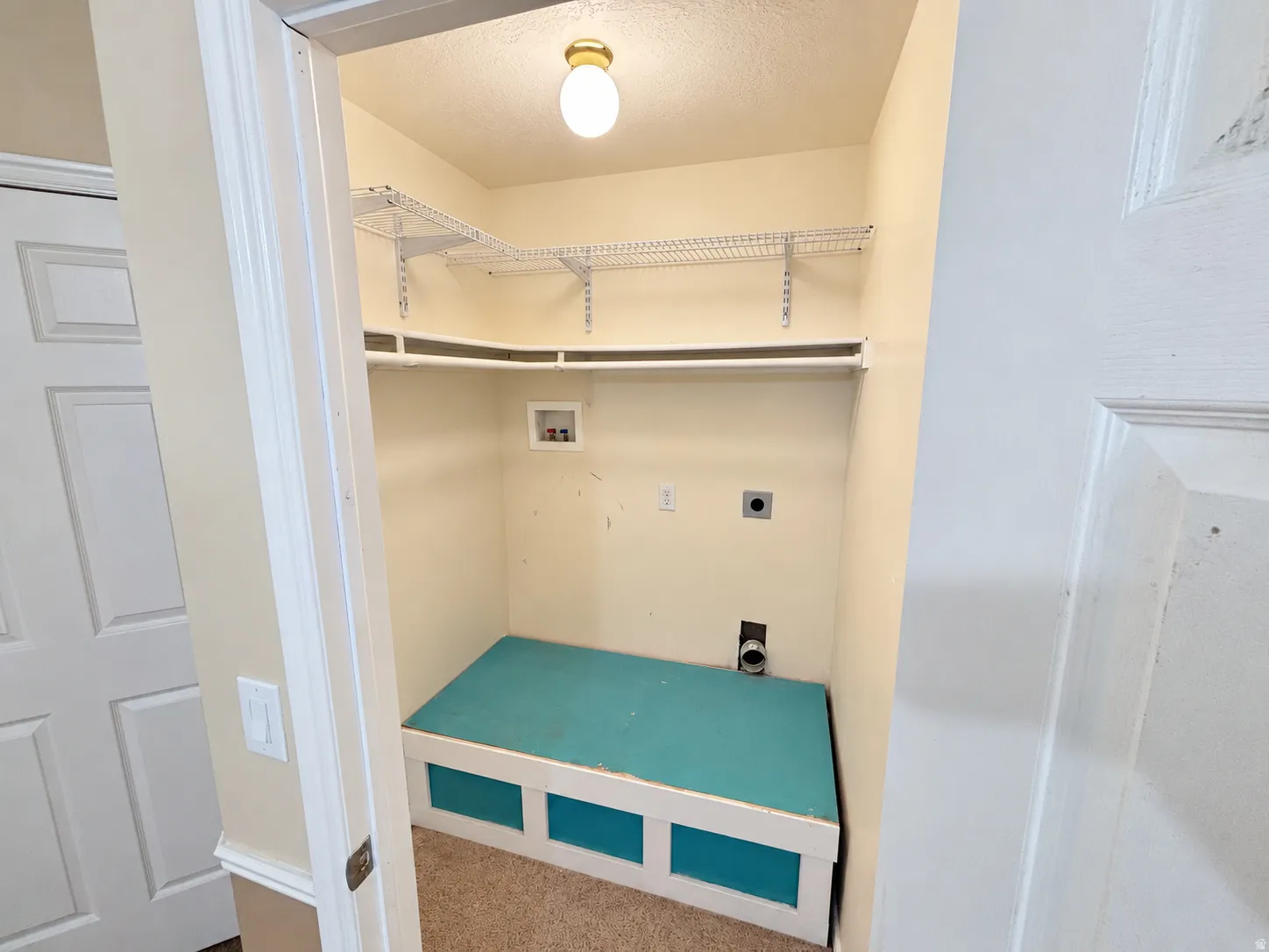 Dedicated laundry space with built-in shelving, hanging rod, and utility connections