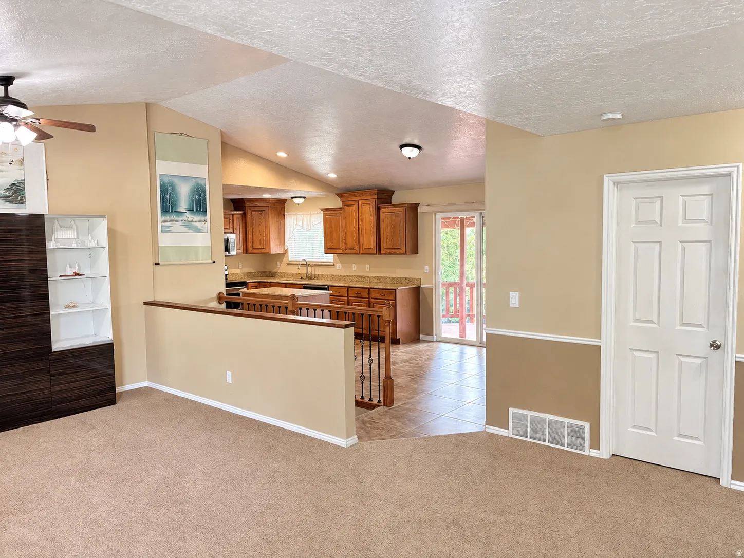 Vaulted ceiling with flush-mount lighting, ceiling fan, and carpeted flooring