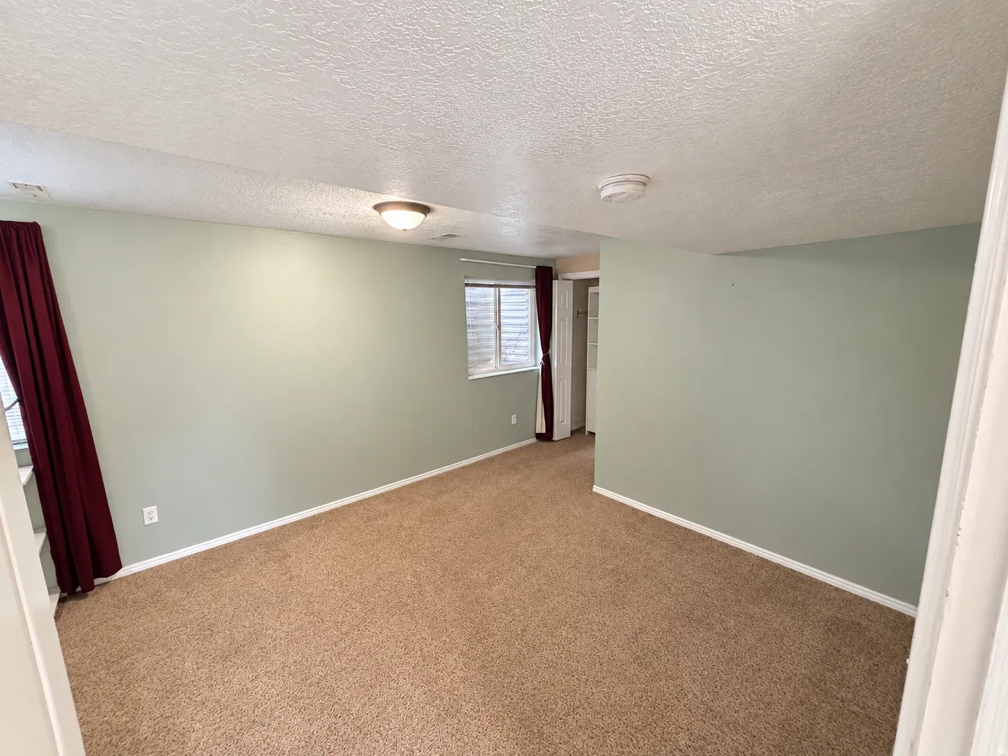 Carpeted flooring, recessed window, overhead lighting, and pale green walls