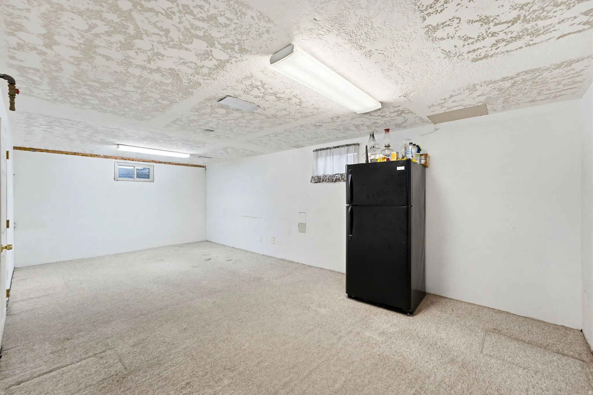 Carpeted room with white walls, a single window, and fluorescent lighting fixtures