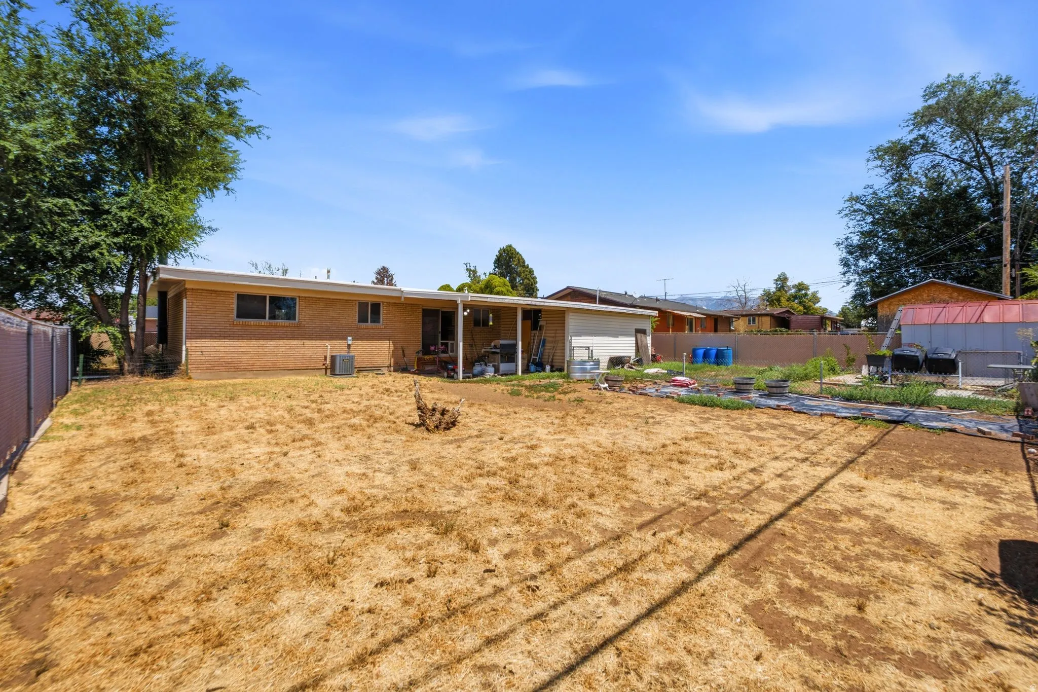 Expansive backyard featuring a large open area, mature perimeter trees, and a brick exterior structure