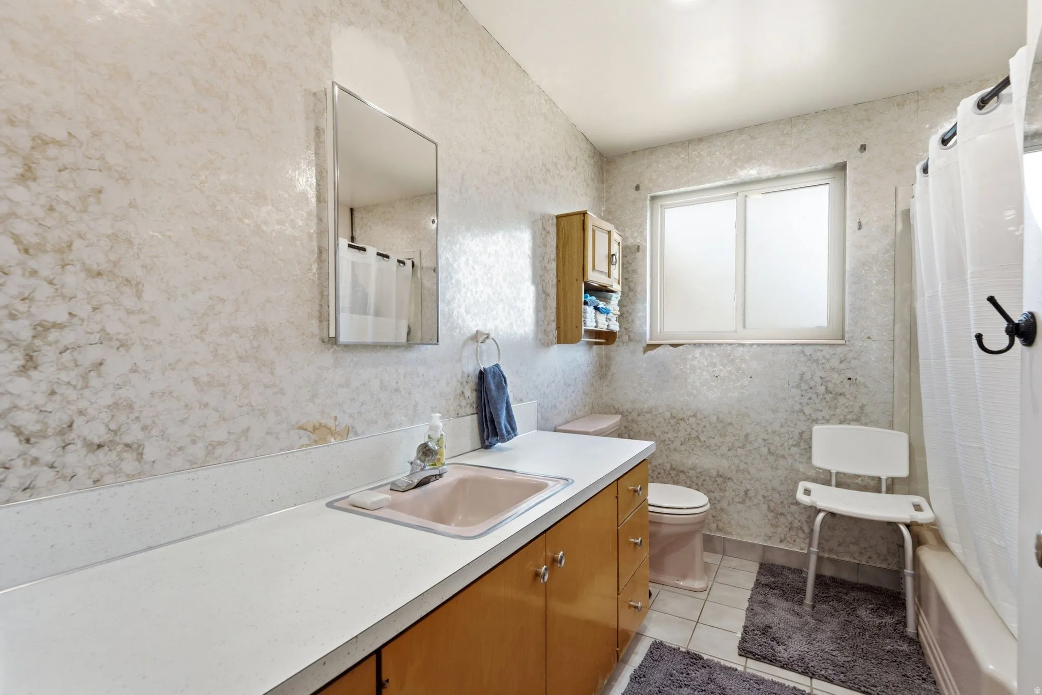 Bathroom featuring a single vanity with a laminate countertop, a drop-in sink, and wood-finish cabinetry