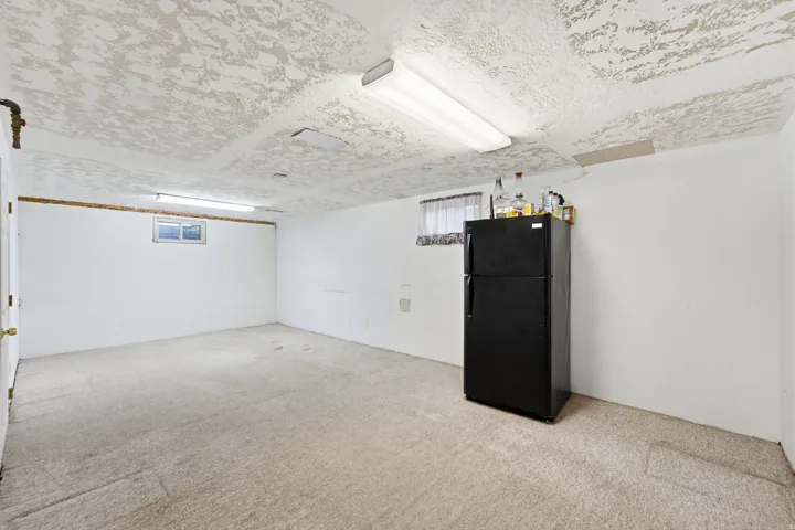 Carpeted room with white walls, a single window, and fluorescent lighting fixtures