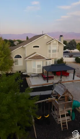 Expansive backyard featuring a concrete patio, covered outdoor living area, and a large playset