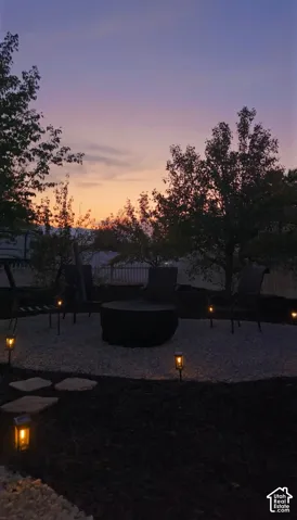 Backyard fire pit area featuring a gravel surface, stone pathway, and landscape lighting