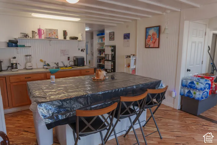 Kitchen space featuring an expansive center island, wood-finish flooring, beadboard wall paneling, and an exposed beam ceiling