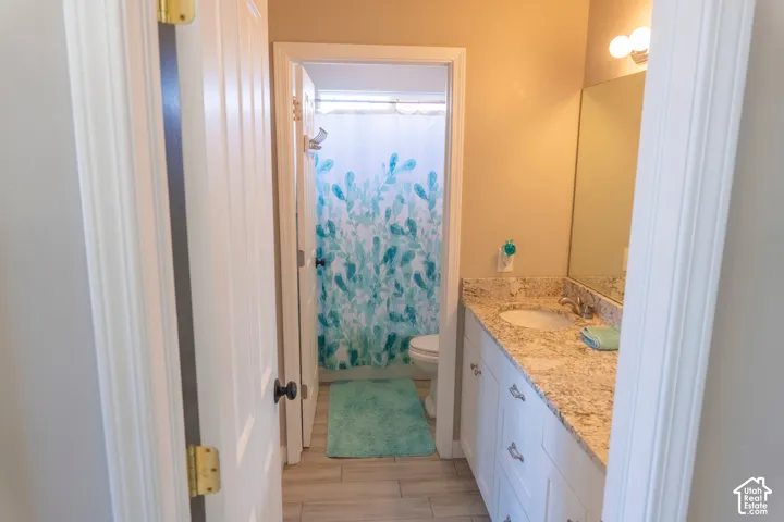 Bathroom featuring a light-toned granite-style countertop, white cabinetry with silver-tone hardware, and a framed mirror