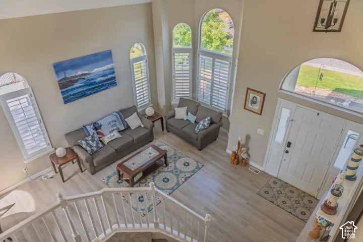Two-story foyer featuring light wood-finish flooring, a white front door with side lites and transom window, and a grand staircase with white railings