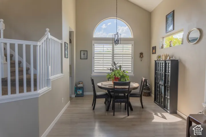 Vaulted ceiling dining area featuring an arched window, white plantation shutters, and wood-finish flooring