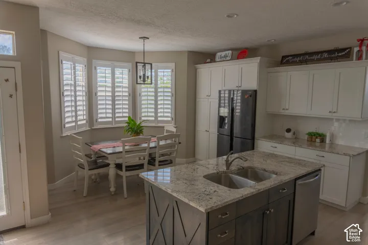 Kitchen featuring a central island with a double basin sink, granite countertops, white cabinetry, and wood-finish flooring