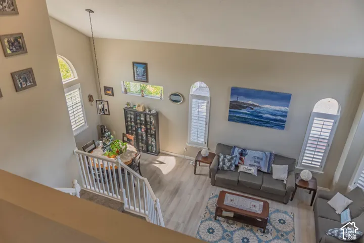 Open-concept living area featuring high ceilings, wood-finish flooring, and multiple arched windows with plantation shutters