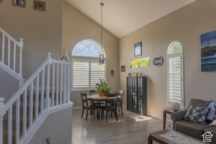 Vaulted ceiling with an arched window, plantation shutters, wood-finish flooring, and white spindle staircase