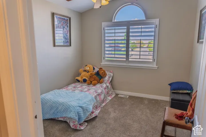 Bedroom featuring a window with plantation shutters and an arched transom, neutral-toned walls, and carpet flooring
