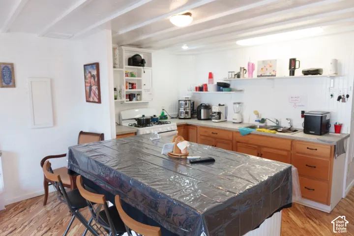 Kitchen with wood-finish flooring and exposed beam ceiling