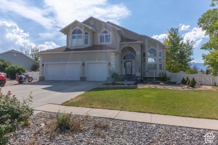 Stucco exterior with arched entry, two-car garage, and multiple large windows
