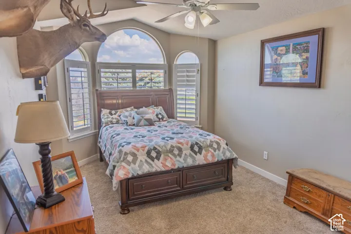 Bedroom featuring an arched window, plantation shutters, and a ceiling fan