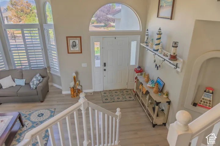 Entryway featuring a white paneled front door with a transom window, wood-finish flooring, and a white staircase with a matching railing