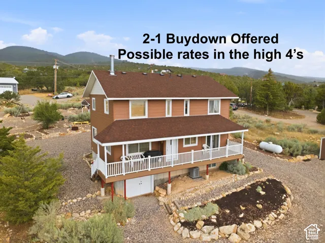 Multi-level residence featuring wood-style siding, a covered deck with white railing, and a mountain backdrop