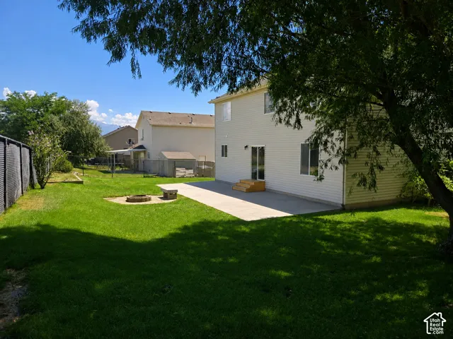 Spacious backyard featuring a concrete patio, built-in fire pit with stone seating, and a privacy fence