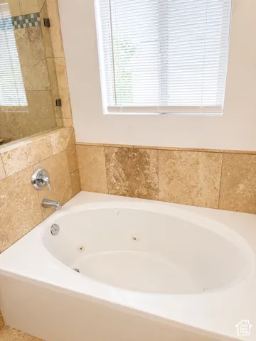 Integrated jetted tub with polished chrome fixtures, surrounded by natural stone-look tile