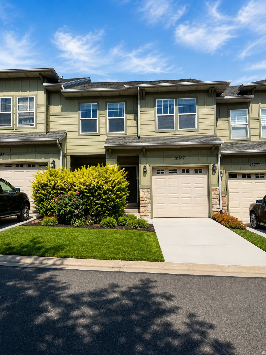Contemporary townhouse exterior featuring a neutral green siding, a two-car garage, and a concrete driveway